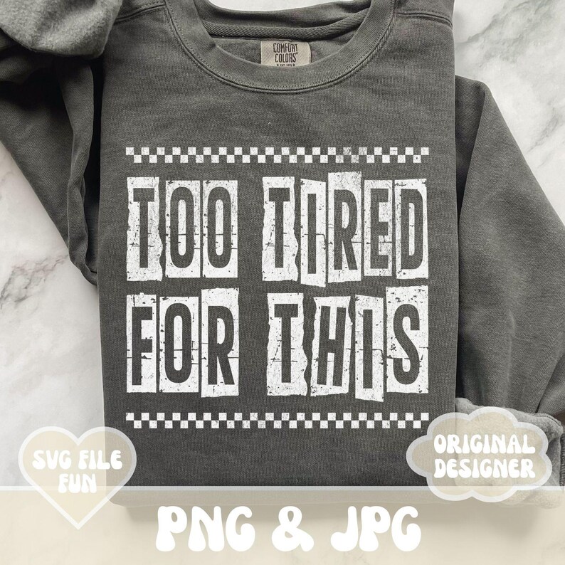 以下が含まれることがあります： グレーのトレーナーに、白いブロック体で「Too Tired For This」という文字が書かれています。文字は、白黒の市松模様の枠で囲まれています。