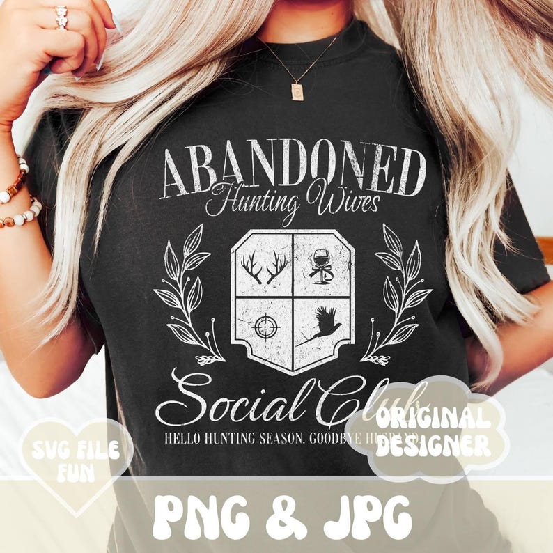 May include: A black t-shirt with a white graphic design that says "Abandoned Hunting Wives Social Club" with a crest featuring hunting-related icons. The text "Hello Hunting Season, Goodbye Husband" is also included in the design.
