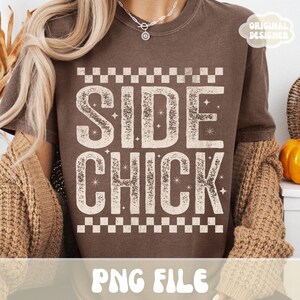 Może przedstawiać: Brązowa koszulka z napisem "SIDE CHICK" w postarzanym, złamanym białym kroju pisma. Tekst jest obramowany wzorem w szachownicę u g&oacute;ry i u dołu. Słowa "PNG FILE" znajdują się na dole koszulki. Słowa "ORIGINAL DESIGNER" znajdują się w prawym g&oacute;rnym rogu.