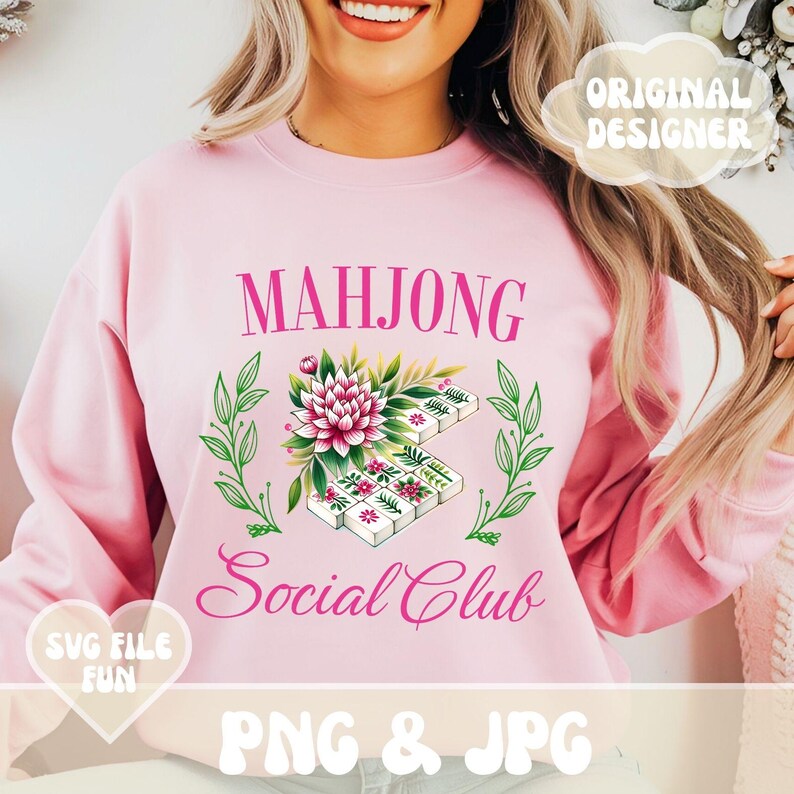 Puede incluir: Sudadera rosa con el texto "Mahjong Social Club" en letras rosas. Un dise&ntilde;o floral con fichas de mahjong blancas est&aacute; por encima del texto.