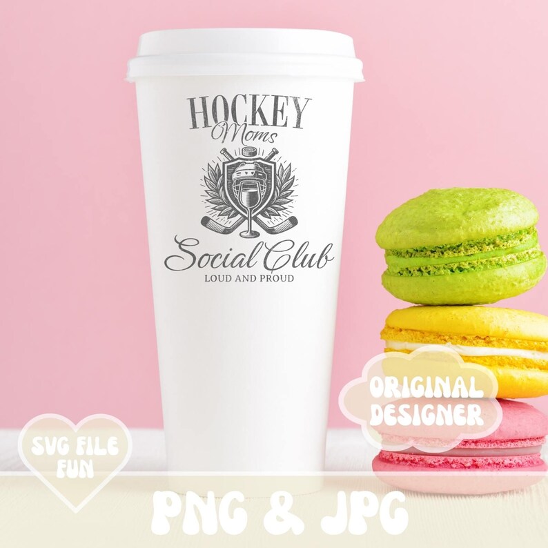 May include: White coffee cup with a black and white graphic design that says "Hockey Moms Social Club Loud and Proud". The graphic features a hockey helmet, crossed hockey sticks, and a glass of wine. The cup is sitting on a pink surface with a stack of colorful macarons.