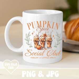 May include: White ceramic mug with the text "Pumpkin Spice Social Club" in orange. The mug features illustrations of pumpkin spice lattes and a small pumpkin. The phrase "Feelin' a little spicy" is also included.