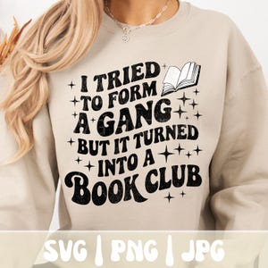 May include: Beige sweatshirt with the text "I tried to form a gang but it turned into a book club" in black. The design includes an open book graphic and star accents. The bottom of the image shows the file types: SVG, PNG, and JPG.