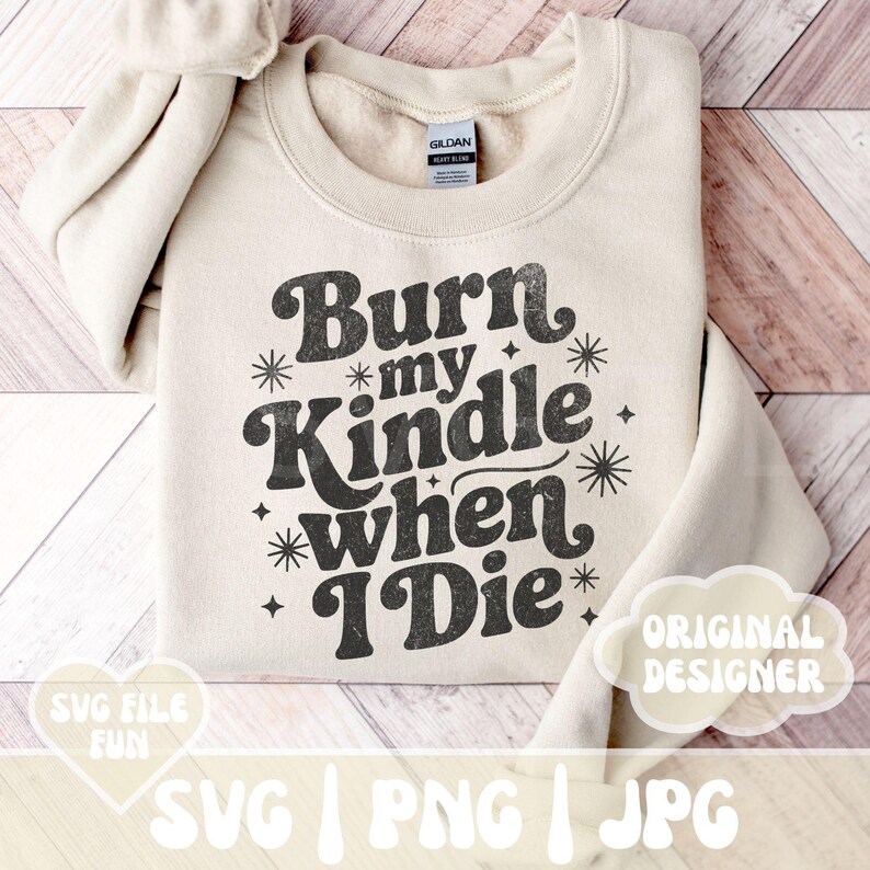 May include: A cream-colored sweatshirt with the text "Burn my Kindle when I Die" in a retro font. The design includes starburst and star accents. The sweatshirt also has the text "SVG FILE FUN" and "ORIGINAL DESIGNER".