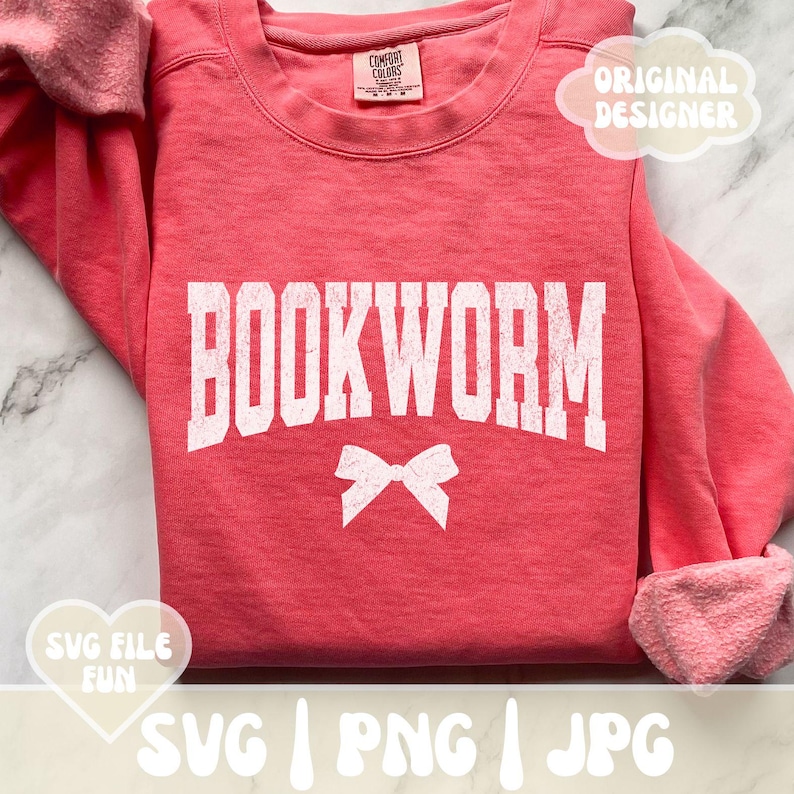 May include: A pink sweatshirt with the word "BOOKWORM" in white with a distressed look. A white bow is below the word. The sweatshirt is folded in half.