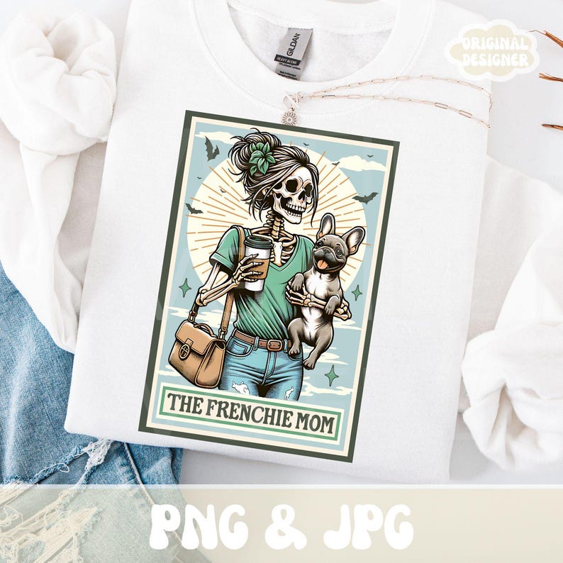 May include: White sweatshirt featuring a graphic of a skeleton holding a coffee cup and a French Bulldog. The graphic is in a rectangular frame with the text "THE FRENCHIE MOM". The design includes bats, stars, and a sunburst background.