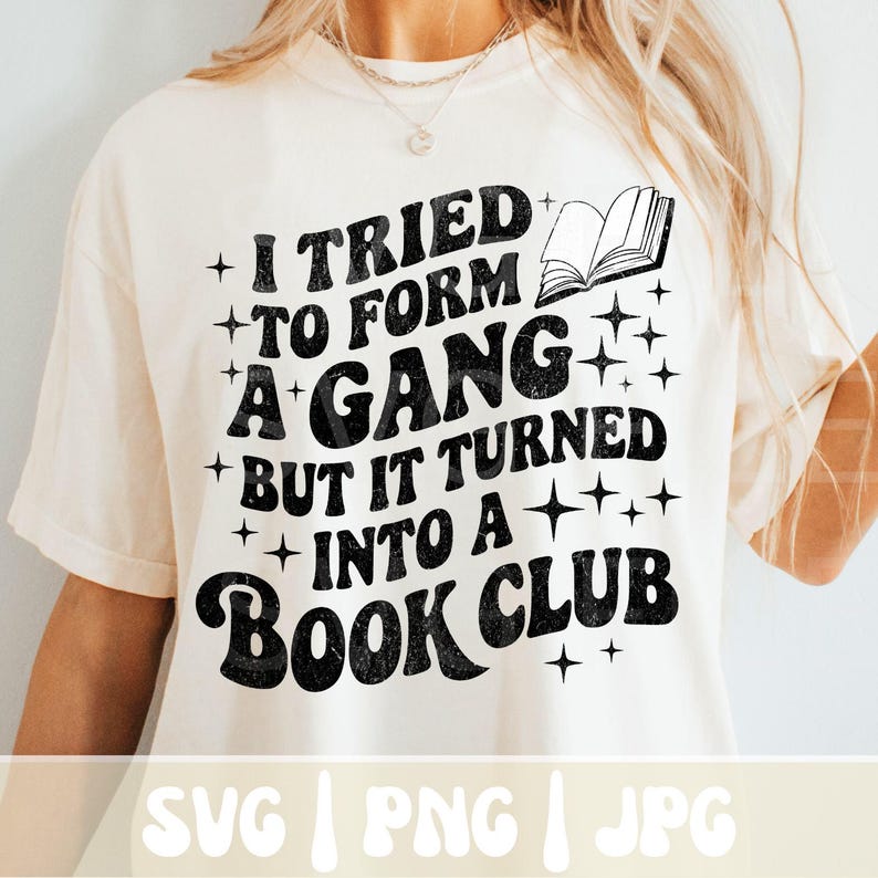 May include: Cream-colored t-shirt with the text "I TRIED TO FORM A GANG BUT IT TURNED INTO A BOOK CLUB" in black. The design includes a book graphic and star accents. The bottom of the shirt has the text "SVG | PNG | JPG".