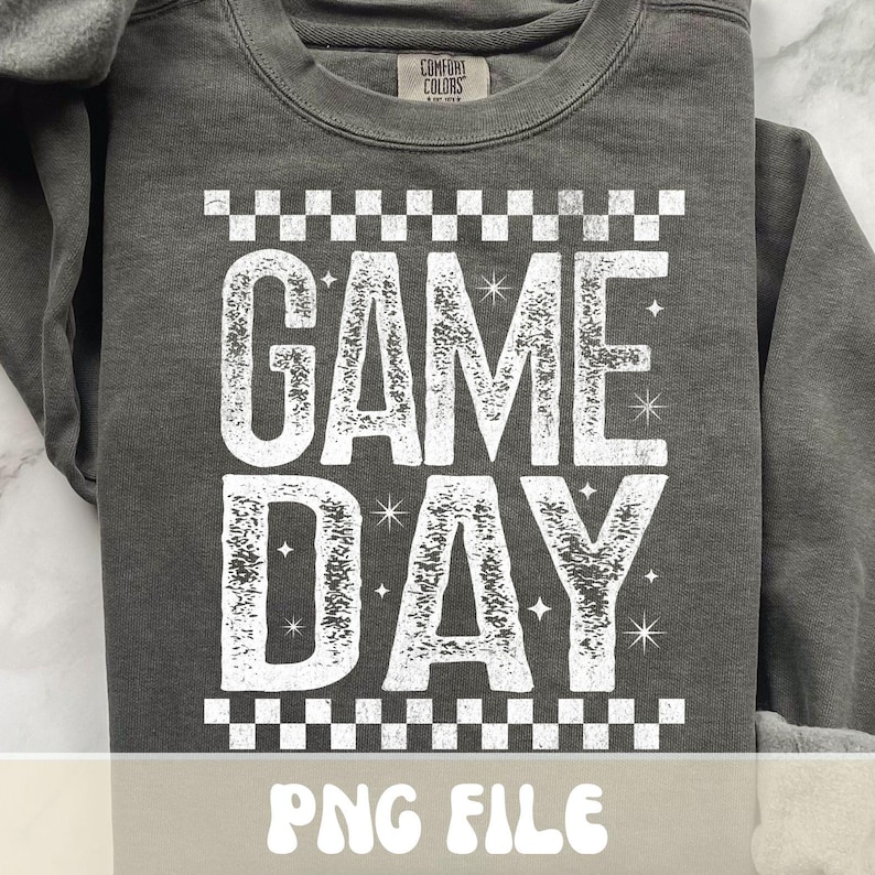 K&ouml;nnte beinhalten: Dunkelgraues Sweatshirt mit dem Schriftzug "GAME DAY" in gro&szlig;en, verblichenen wei&szlig;en Buchstaben. Der Text wird von einem Schachbrettmuster oben und unten eingerahmt. Das Sweatshirt hat einen Rundhalsausschnitt und lange &Auml;rmel.