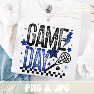 May include: White sweatshirt with a "GAME DAY" graphic in black and blue. The design includes a lacrosse stick, a star, and a lightning bolt. The text "PNG & JPG" is at the bottom.