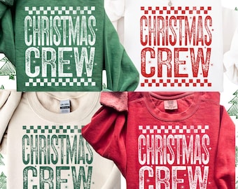 May include: Four sweatshirts in green, white, cream, and red, each with the text "CHRISTMAS CREW" in a distressed font. The text is framed by a checkered pattern. The sweatshirts are crew neck style.