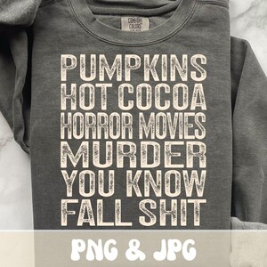 Puede incluir: Sudadera gris oscuro con la frase blanca "PUMPKINS HOT COCOA HORROR MOVIES MURDER YOU KNOW FALL SHIT". La sudadera tiene cuello redondo y mangas largas. El texto "PNG & JPG" est&aacute; en la parte inferior.