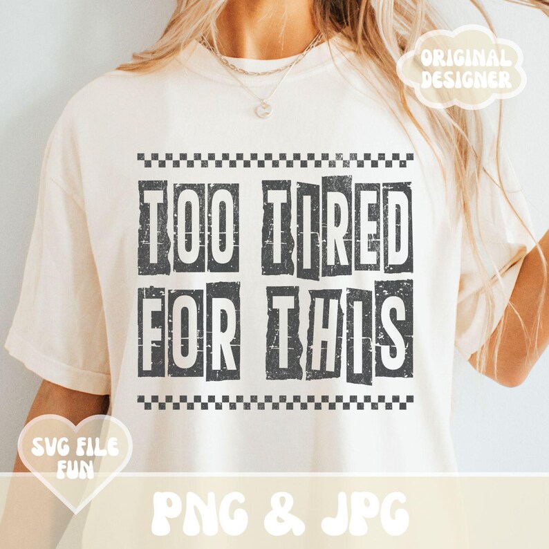 以下が含まれることがあります： 黒い文字で「Too Tired For This」と書いてある白いTシャツ。文字はかすれたようなフォントで、黒と白の市松模様の枠で囲まれている。