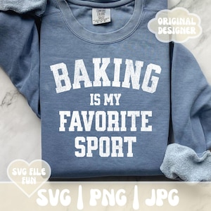 Może przedstawiać: Niebieska bluza z napisem "BAKING IS MY FAVORITE SPORT" białymi literami. Bluza ma okrągły dekolt i długie rękawy. Słowa "SVG FILE FUN" znajdują się w grafice w kształcie serca.