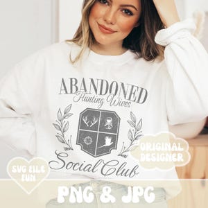 May include: White sweatshirt with the text "Abandoned Hunting Wives Social Club" in a vintage style font. The text is surrounded by a grey crest with hunting-related imagery. The text "Original Designer" is in a cloud shape in the top right corner. The text "SVG File Fun" is in a heart shape in the bottom left corner. The text "PNG & JPG" is in a large, colourful font at the bottom of the image.