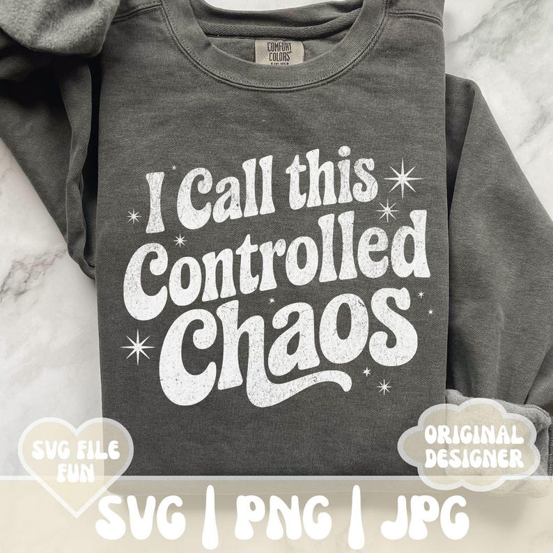 May include: Dark gray sweatshirt with the text "I Call this Controlled Chaos" in white, retro-style font. The sweatshirt has a crew neck and long sleeves. The image also includes the text "SVG FILE FUN" and "ORIGINAL DESIGNER".