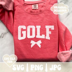 May include: A pink sweatshirt with the word "GOLF" in white with a white bow underneath. The sweatshirt has a distressed look.