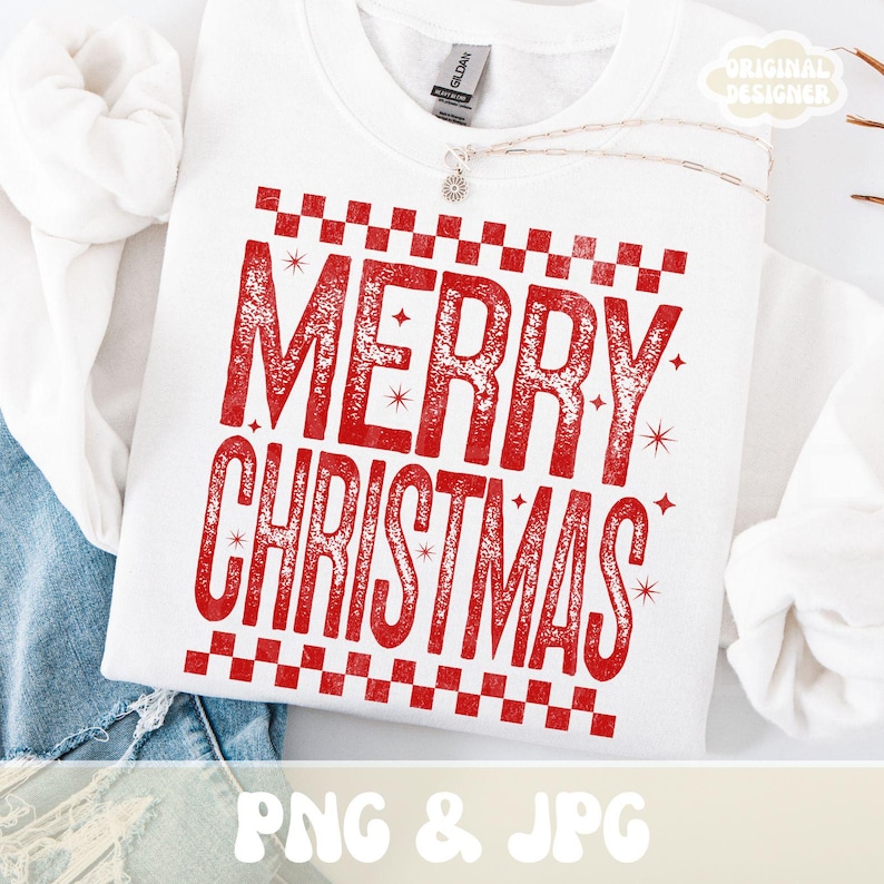 May include: White crew neck sweatshirt with a red "MERRY CHRISTMAS" graphic. The text is in a distressed font, framed by a checkered pattern. The sweatshirt has a "GILDAN" tag. A silver necklace with a pendant is visible.