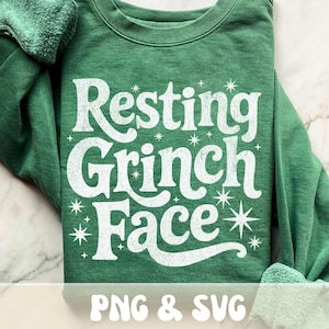 May include: A green sweatshirt with the phrase "Resting Grinch Face" in large, distressed white lettering. The design includes starburst accents. The bottom of the image includes the text "PNG & SVG".