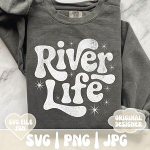 May include: Dark gray sweatshirt with the words "River Life" in a white, retro font. The design includes starburst accents. The sweatshirt also has the text "SVG FILE FUN" and "ORIGINAL DESIGNER".