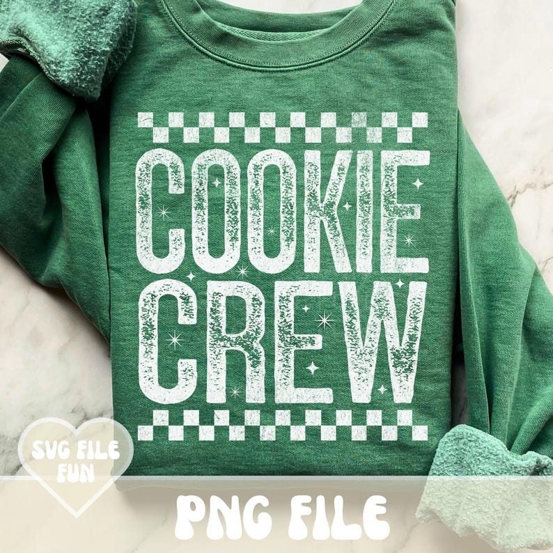May include: Green sweatshirt with the words "COOKIE CREW" in large, white, distressed lettering. The design includes a checkered pattern above and below the text, with star accents. The phrase "SVG FILE FUN" and "PNG FILE" are also visible.