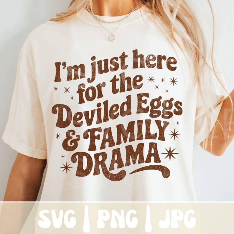 Puede incluir: Camiseta color crema con la frase marr&oacute;n "I'm just here for the Deviled Eggs & FAMILY DRAMA" en tipograf&iacute;a retro, adornada con estrellas. Dise&ntilde;o sencillo y casual.