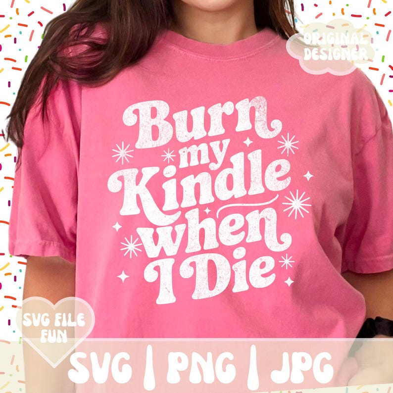 May include: Pink t-shirt with the text "Burn my Kindle when I Die" in a retro white font. The shirt has a relaxed fit and short sleeves. The design includes starburst and star accents.