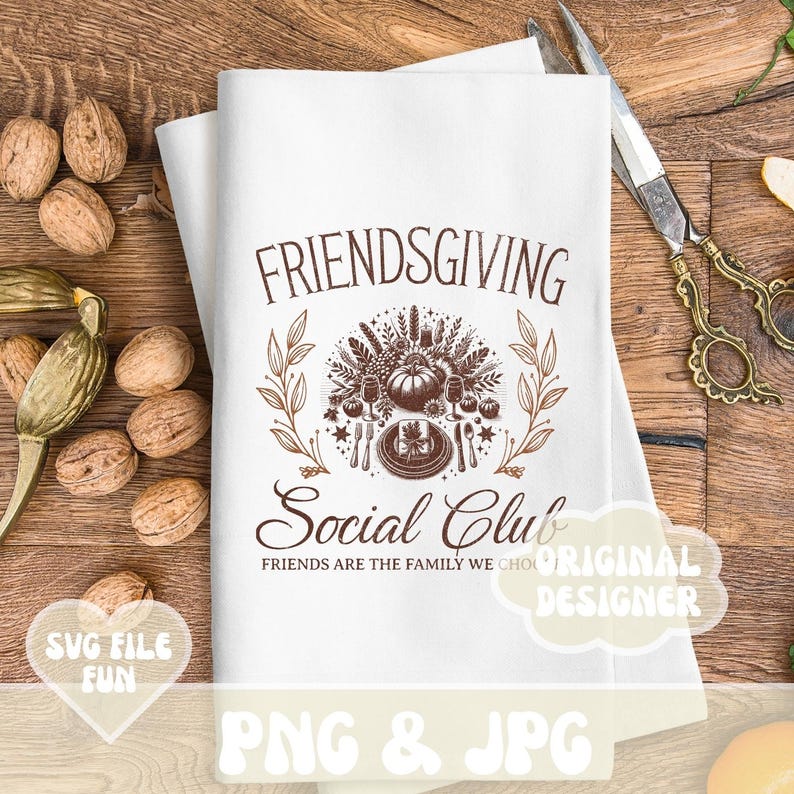 May include: White Friendsgiving Social Club kitchen towel with a brown graphic design. The design includes a pumpkin, wheat, and cutlery. The text reads "FRIENDSGIVING Social Club" and "FRIENDS ARE THE FAMILY WE CHOOSE".