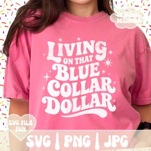 May include: A pink t-shirt with the text "Living on that Blue Collar Dollar" in a retro font. The shirt also has the text "SVG File Fun" and "Original Designer". The shirt is a casual style.