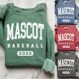 May include: A collection of sweatshirts in various colors, each featuring the text "MASCOT BASEBALL 2026" in a bold, white font. The sweatshirts are in shades of green, blue, red, and gray, with a classic crew neck design.