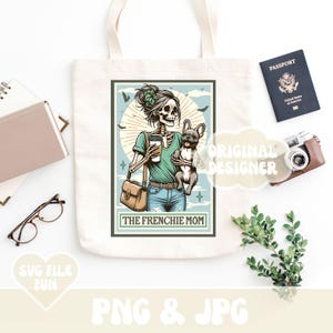 May include: A cream-colored tote bag featuring a graphic of a skeleton woman holding a coffee and a French Bulldog. The text "THE FRENCHIE MOM" is below the image. A passport, camera, and glasses are also visible.