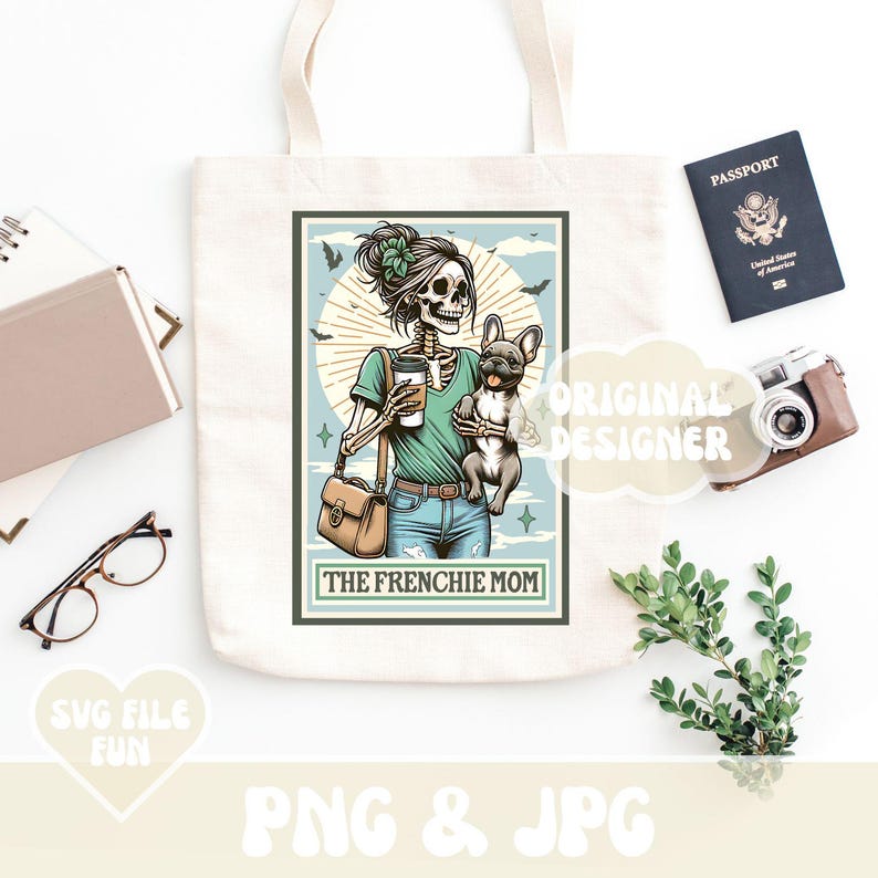 May include: A cream-colored tote bag featuring a graphic of a skeleton woman holding a coffee and a French Bulldog. The text "THE FRENCHIE MOM" is below the image. A passport, camera, and glasses are also visible.