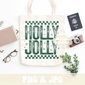 May include: A cream tote bag printed with the words "HOLLY JOLLY" in green, distressed lettering. The image includes a passport, a vintage camera, glasses, and a notebook, all on a white surface.