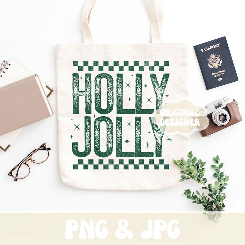 May include: A cream tote bag printed with the words "HOLLY JOLLY" in green, distressed lettering. The image includes a passport, a vintage camera, glasses, and a notebook, all on a white surface.