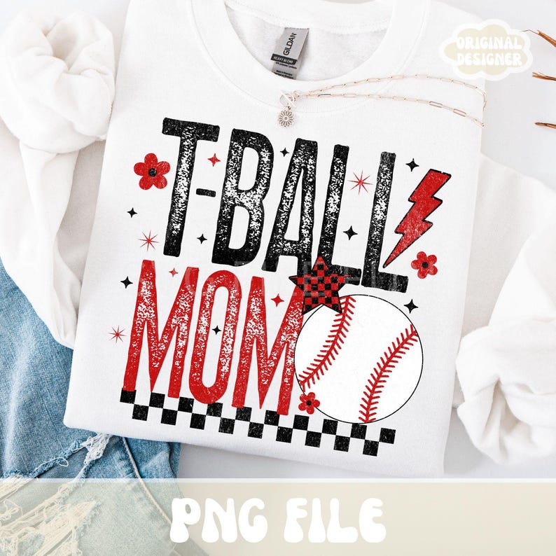 May include: White sweatshirt with the text "T-BALL MOM" in black and red. The design includes a baseball, stars, a lightning bolt, and floral accents. The sweatshirt is a Gildan brand.