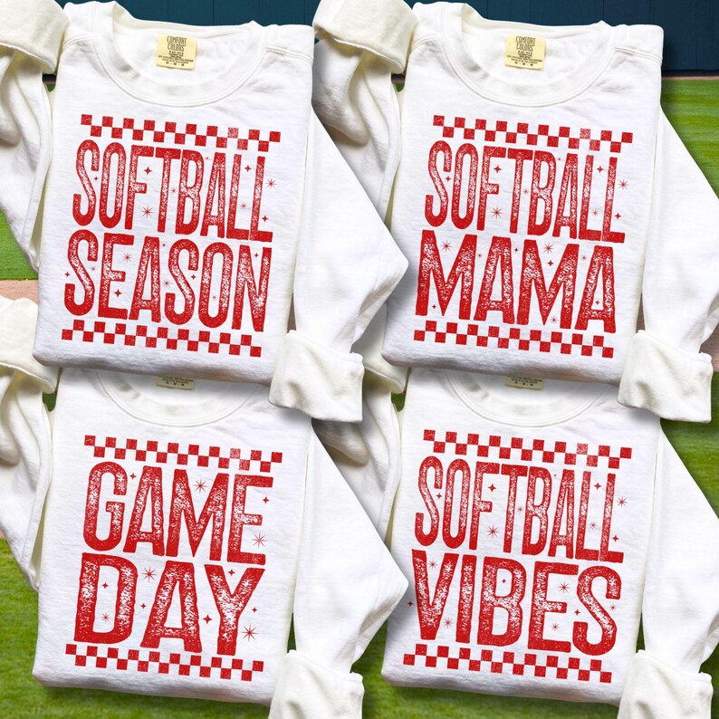 May include: Four white long-sleeved shirts with red text. The shirts have different phrases: "SOFTBALL SEASON", "SOFTBALL MAMA", "GAME DAY", and "SOFTBALL VIBES". Each phrase is in a bold, stylized font with a checkered border.