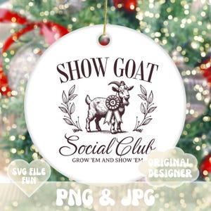 May include: White ceramic ornament with a brown illustration of a goat wearing a ribbon with the number one on it. The text "SHOW GOAT Social Club GROW 'EM AND SHOW 'EM ORIGINAL DESIGNER" is printed on the ornament.