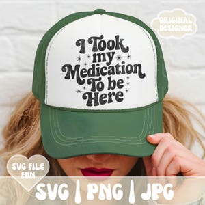 Könnte beinhalten: Grün-weiße Trucker-Mütze mit dem Text "I Took my Medication To be Here" in Schwarz. Die Mütze hat einen gebogenen Schirm und einen Mesh-Rücken. Das Design enthält Sterne.