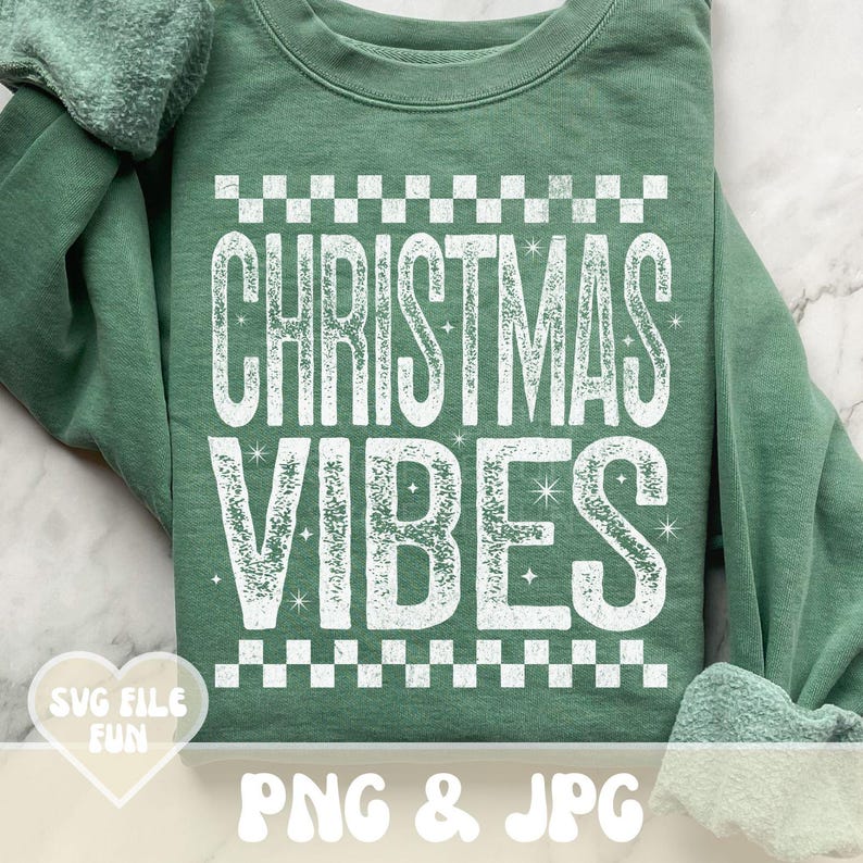 May include: A sage green sweatshirt featuring the words "CHRISTMAS VIBES" in large, distressed white letters, framed by a checkered pattern. The bottom of the sweatshirt has the text "PNG & JPG".
