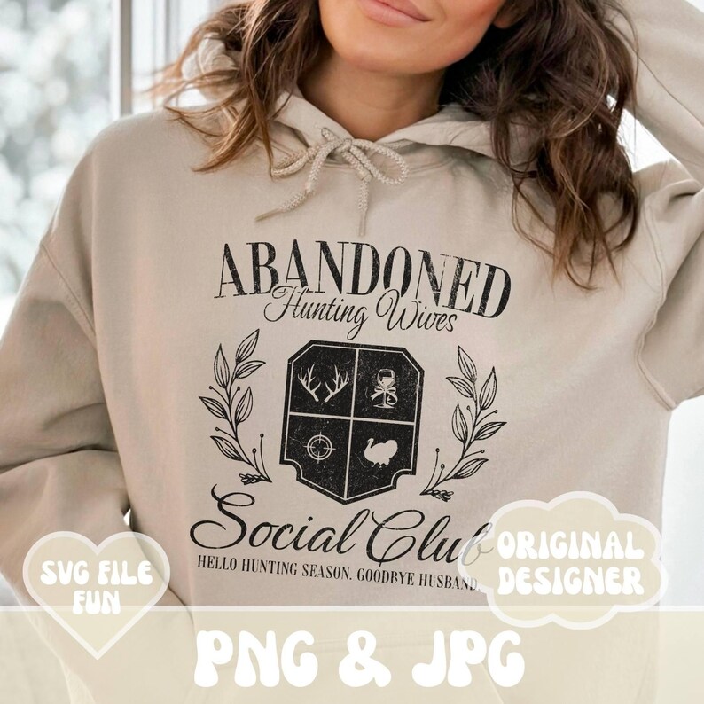 Może przedstawiać: Beżowa bluza z kapturem z czarnym nadrukiem graficznym, na kt&oacute;rym widnieje napis "Abandoned Hunting Wives Social Club" wraz z herbem przedstawiającym symbole związane z polowaniem. Pod herbem znajduje się napis "Hello Hunting Season, Goodbye Husband". Napis "Original Designer" znajduje się w kształcie chmury po prawej stronie obrazu. Napis "SVG File Fun" znajduje się w kształcie serca po lewej stronie obrazu. Napis "PNG & JPG" znajduje się na dole obrazu.