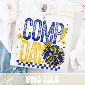 May include: White sweatshirt with the words "COMP DAY" in blue and yellow. The design includes a lightning bolt, stars, flowers, and a pom-pom. The words are in a distressed, vintage style. The phrase "PNG FILE" is at the bottom.