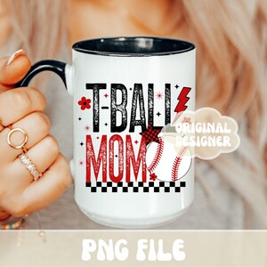 May include: White ceramic mug with black handle and rim, featuring the text "T-BALL MOM" in black and red. A baseball graphic and decorative elements complete the design. The mug is a PNG file.