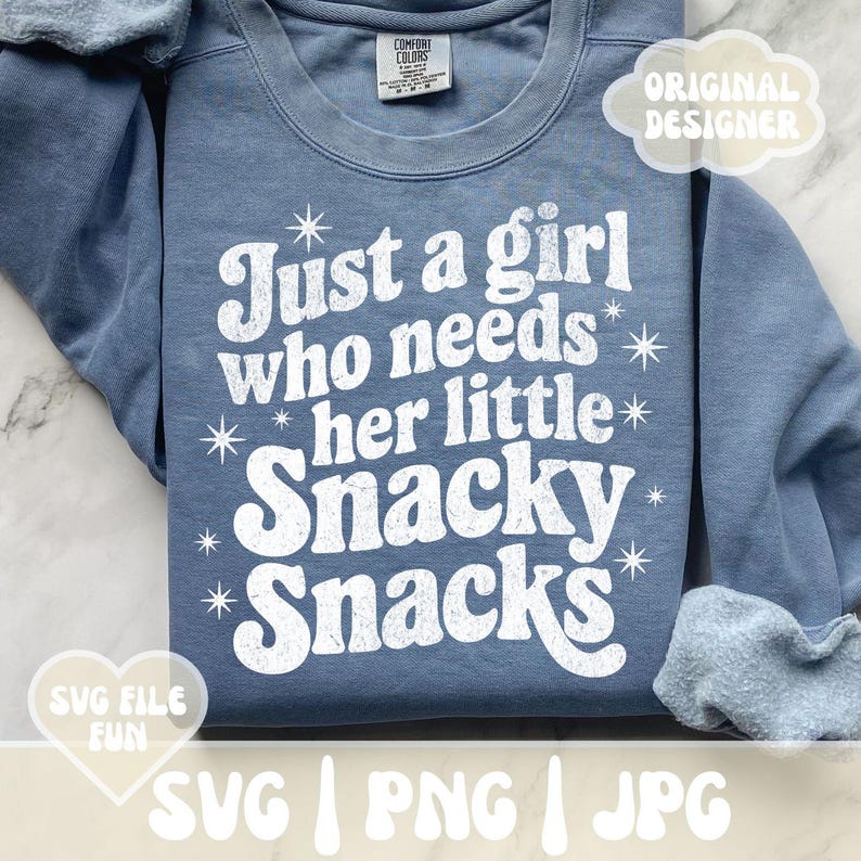 May include: A blue Comfort Colors sweatshirt with the text "Just a girl who needs her little Snacky Snacks" in white. The design includes star accents. The image also shows "Original Designer" and "SVG File Fun" graphics.