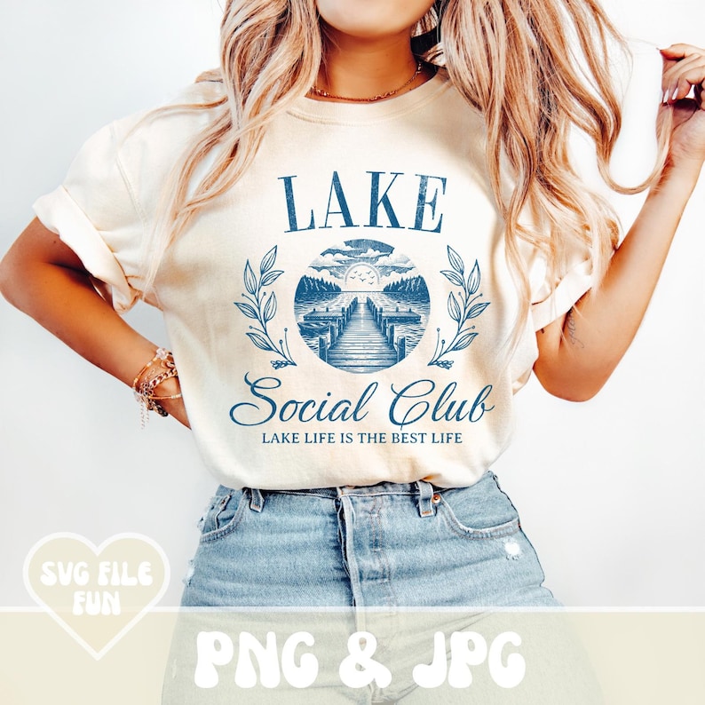May include: A white t-shirt with a blue graphic design that says "LAKE Social Club LAKE LIFE IS THE BEST LIFE". The graphic features a lake scene with a dock and a sun.