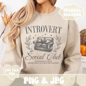 May include: A beige sweatshirt with the text "INTROVERT Social Club" and the words "INTROVERTS UNITE SEPARATELY IN YOUR OWN HOMES" printed on it. The design features a vintage-style illustration of a couch with a floral motif.