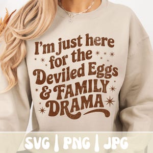 Puede incluir: Sudadera beige con el texto marr&oacute;n "I'm just here for the Deviled Eggs & FAMILY DRAMA". El dise&ntilde;o incluye acentos de estrellas. La parte inferior de la imagen muestra "SVG | PNG | JPG".
