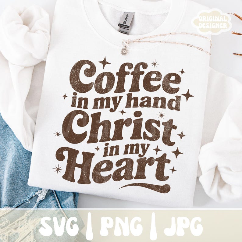 May include: White sweatshirt with the text "Coffee in my hand, Christ in my heart" in brown, surrounded by starbursts. The sweatshirt has a crew neck and long sleeves. The bottom of the image shows the file types: SVG, PNG, and JPG.