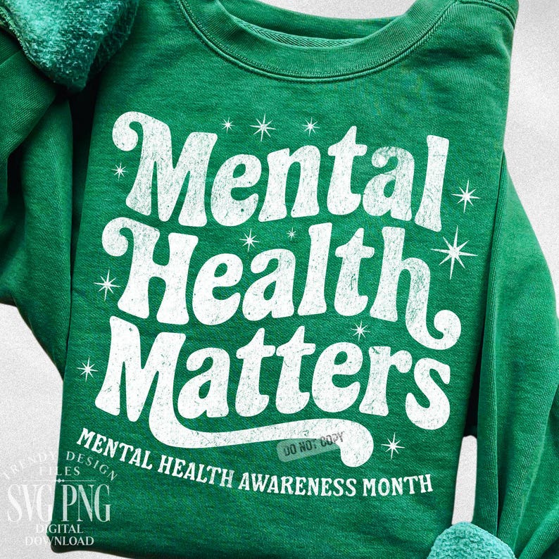 May include: A green sweatshirt with the words "Mental Health Matters" in a distressed white font. The phrase is surrounded by starburst graphics. Below the main text, it reads "Mental Health Awareness Month".