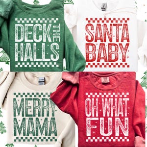 May include: Four crewneck sweatshirts in various colors, each with a holiday-themed graphic. The sweatshirts are green, white, cream, and red. The graphics include the phrases "Deck the Halls", "Santa Baby", "Merry Mama", and "Oh What Fun".