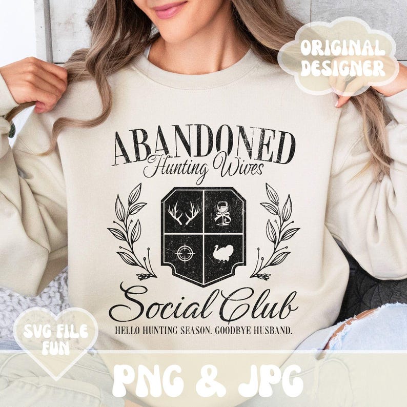 Może przedstawiać: Beżowa bluza z czarnym nadrukiem graficznym, na kt&oacute;rym widnieje napis "Abandoned Hunting Wives Social Club" oraz herb z wizerunkiem indyka, tarczy, jelenia i kieliszka wina. Tekst pod herbem brzmi "Hello Hunting Season. Goodbye Husband."