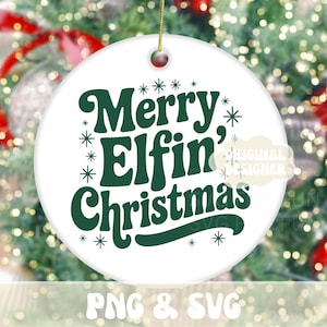 May include: White ceramic Christmas ornament with the text "Merry Elfin' Christmas" in dark green. The ornament has a gold string for hanging and is decorated with snowflakes. The background is a blurred image of a Christmas tree.